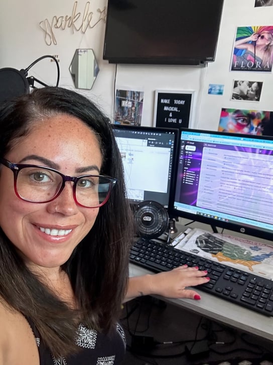 Elisha Mojica sitting and smiling in front of her computer